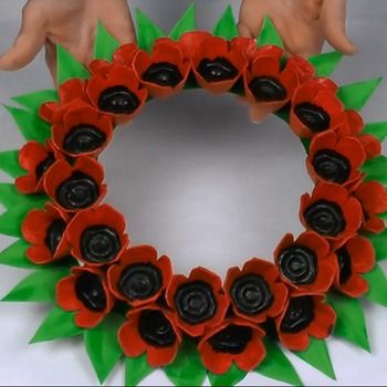 a wreath made out of red and green paper with two hands reaching for the center