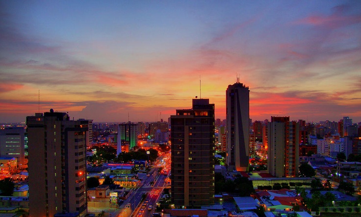 the city skyline is lit up at night with bright lights in the sky and tall buildings