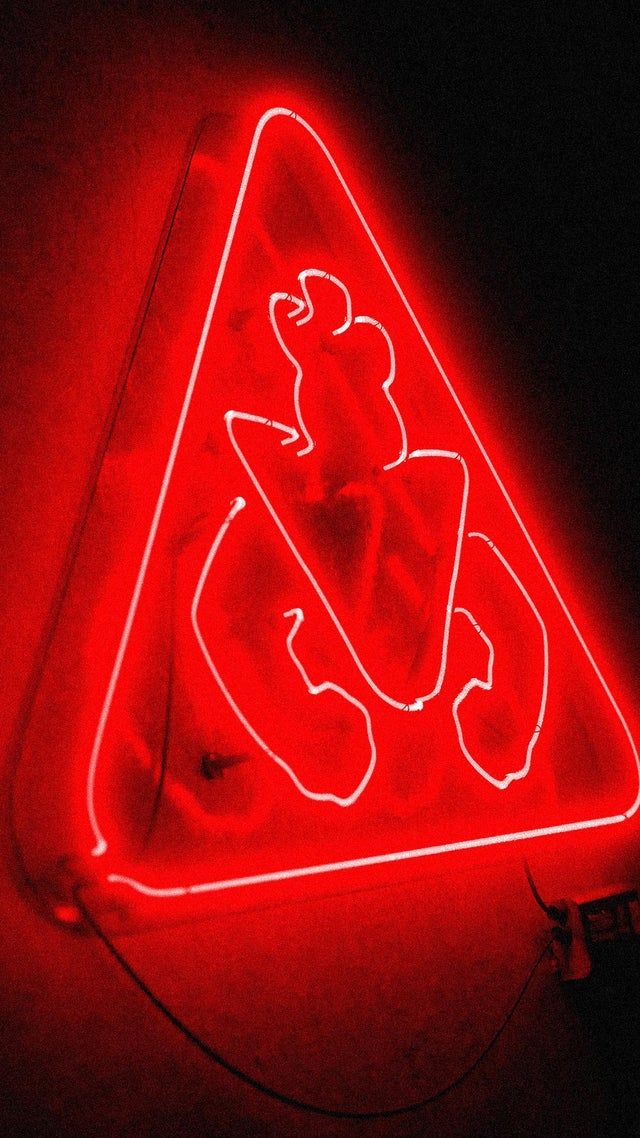 a triangle shaped neon sign that is red