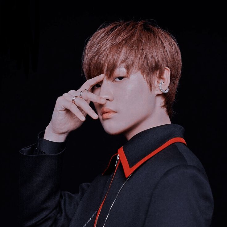 a young man with red hair and piercings on his ears is posing for a photo