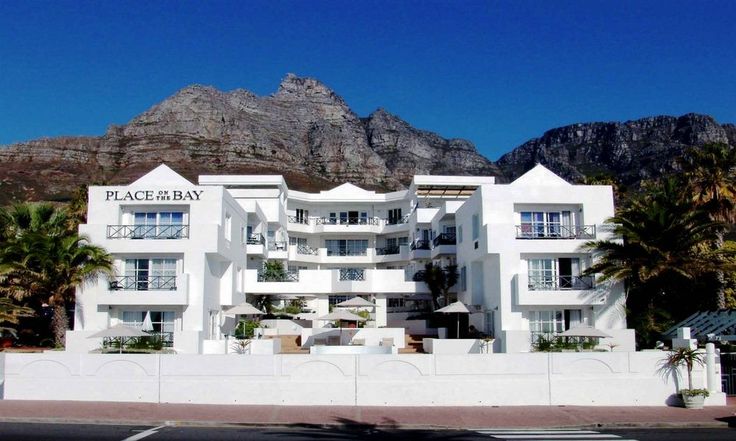 a large white building with palm trees in front of it and mountains in the background