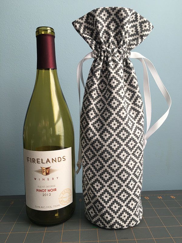 a bottle of wine sitting next to a bag with a tie on it and a bottle of wine in front of it