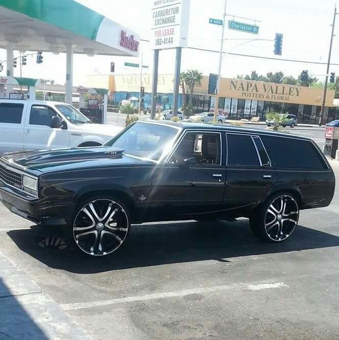 a black station wagon parked in front of a gas station with other cars behind it