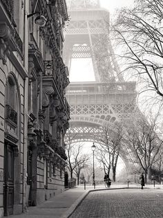 the eiffel tower in black and white with people walking down the street below