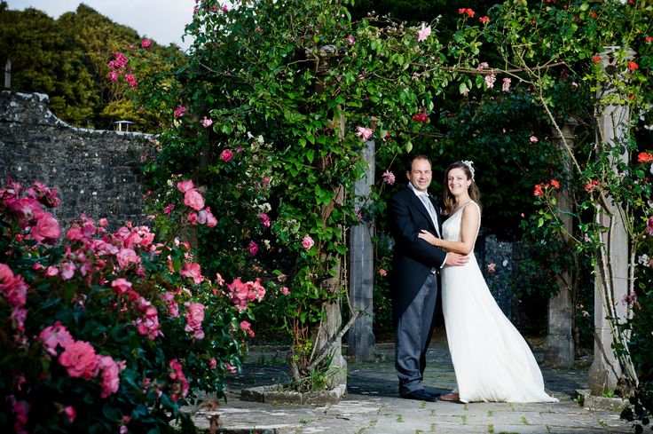 a bride and groom standing in front of some flowers