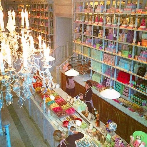 two people are standing at the counter in a store with chandeliers hanging from the ceiling