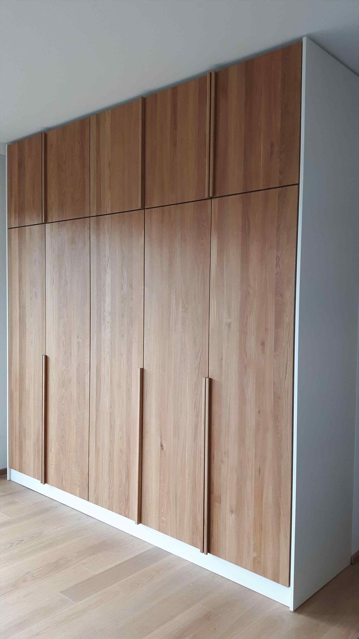 an empty room with wooden cabinets and hard wood flooring on the walls, in front of a large window