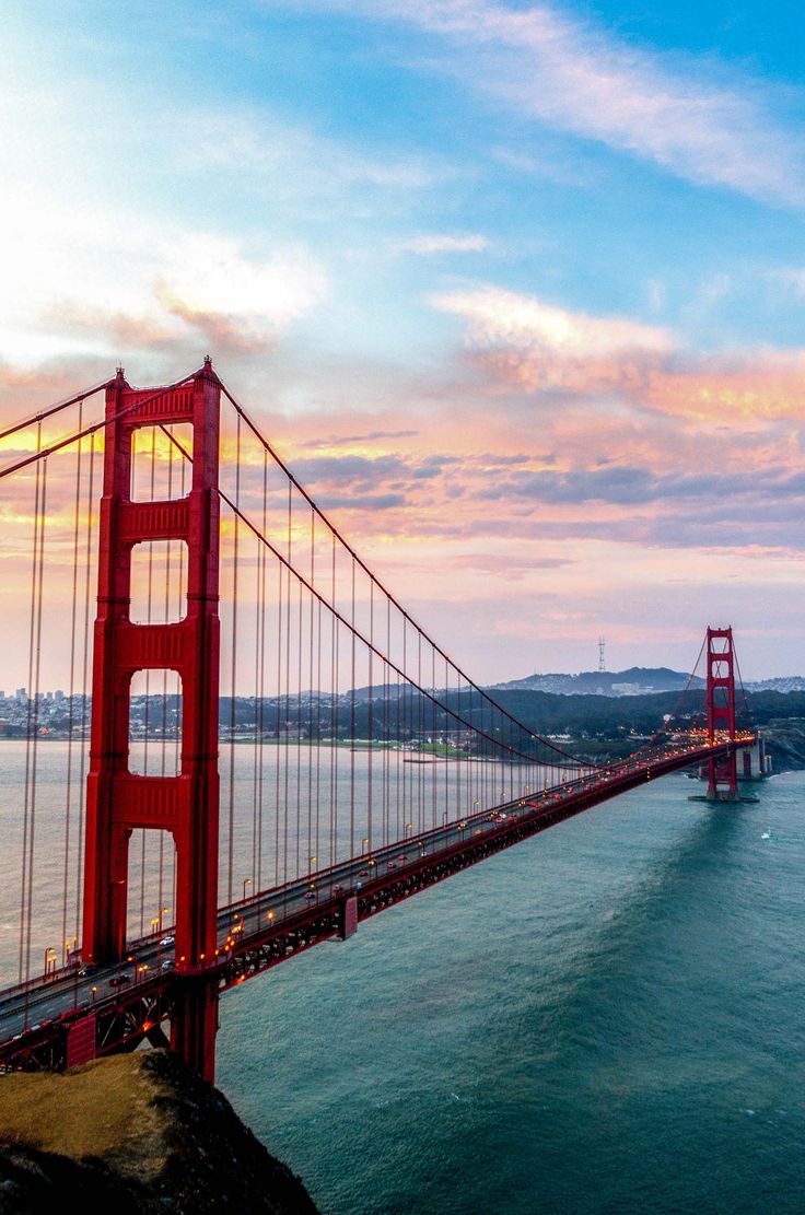 the golden gate bridge in san francisco, california is seen at sunset from across the bay