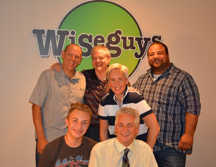 a group of people posing for a photo in front of a wiggegy's sign