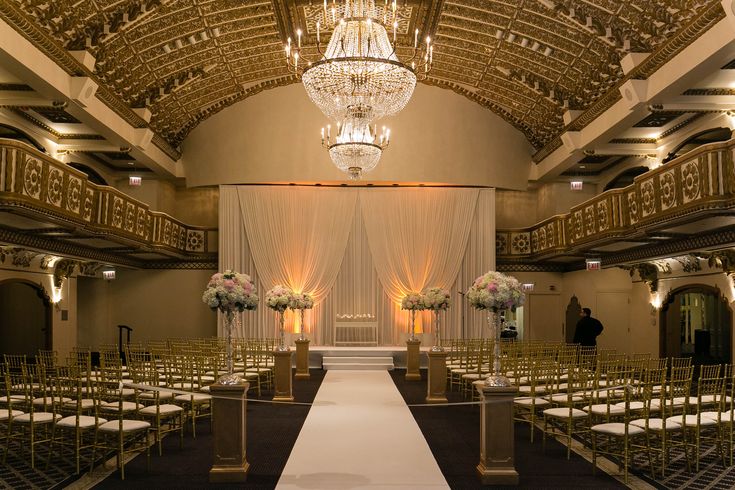 the aisle is lined with white chairs and chandeliers for an elegant wedding ceremony