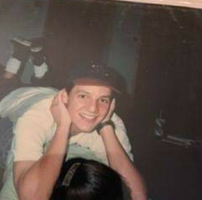 an old photo of a young man sitting in front of a mirror with his hand on his head