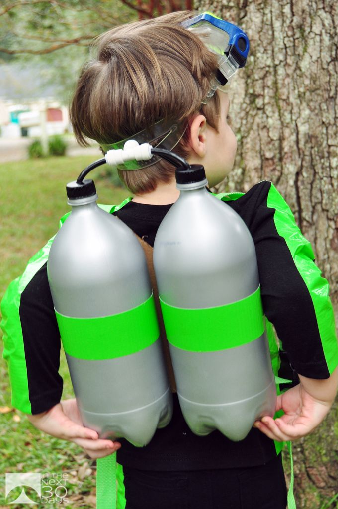 a young boy holding two large gray and green water bottles