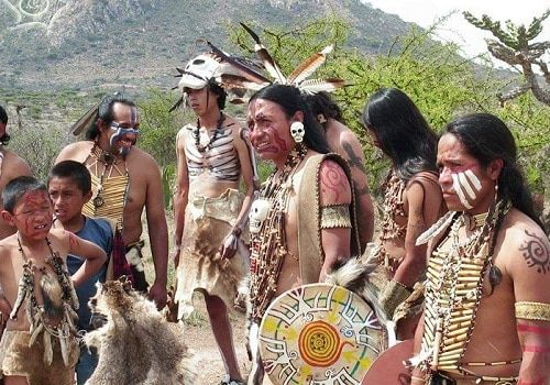 native american people standing in front of a mountain