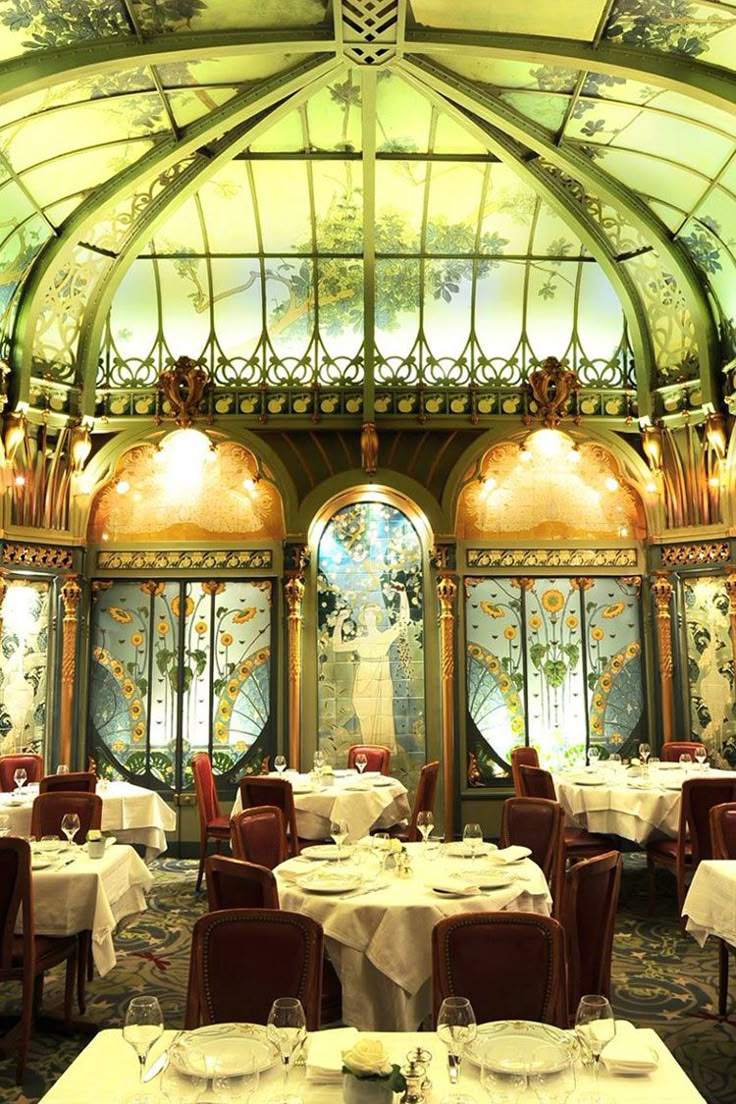 a dining room with tables and chairs covered in white tablecloths under a stained glass ceiling