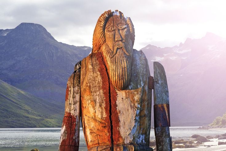 a wooden carving of a man with mountains in the background