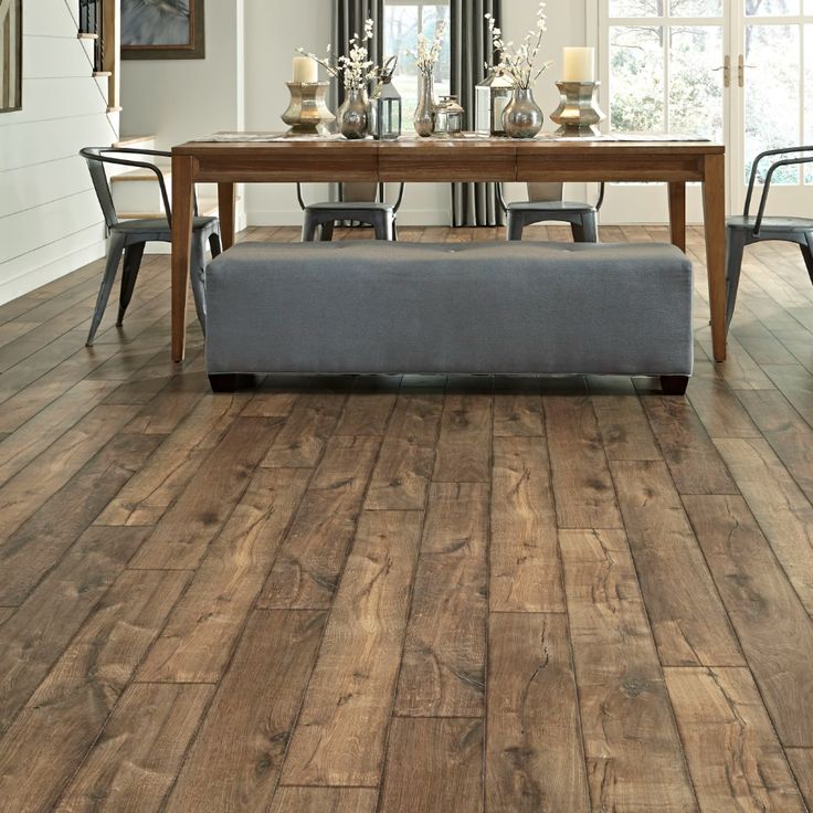 a dining room with wood flooring and a bench in front of a table that has candles on it