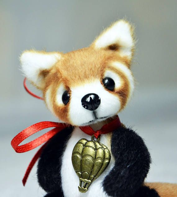 a stuffed animal with a red ribbon around it's neck and an ornament in the shape of a hand