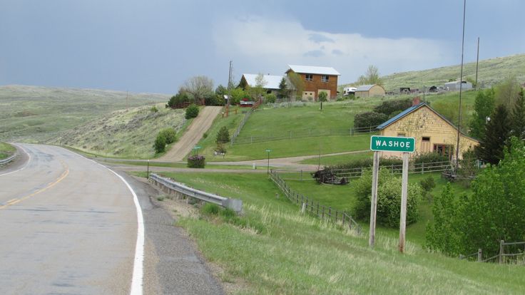 a rural road with houses on the side and a green street sign in the foreground