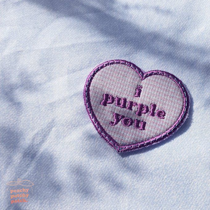 a heart shaped patch with the words i purple you on it sitting on top of a blue shirt