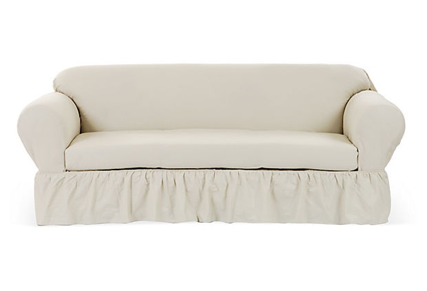 a white couch with a ruffled skirt on it's back and the seat upholstered