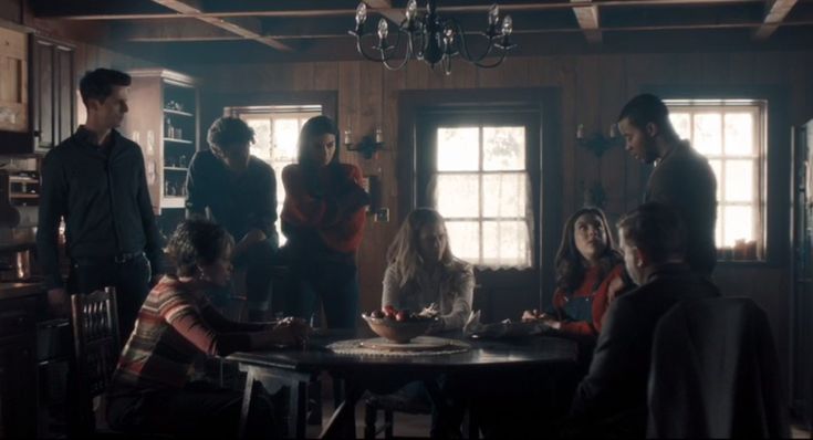 a group of people standing around a kitchen table