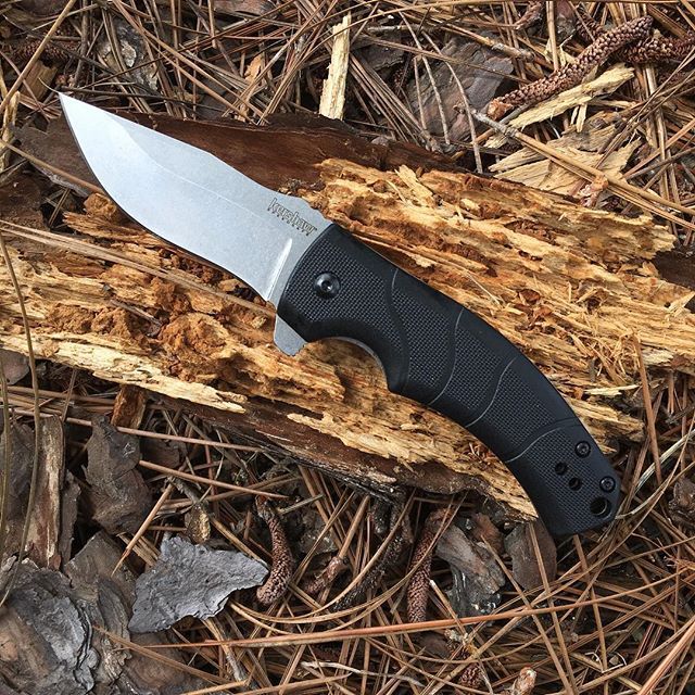 a knife that is laying on the ground next to some leaves and wood chips in the woods