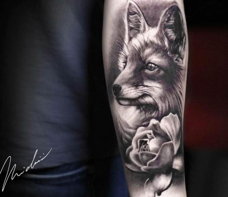 a man's arm with a black and white tattoo of a fox holding a rose