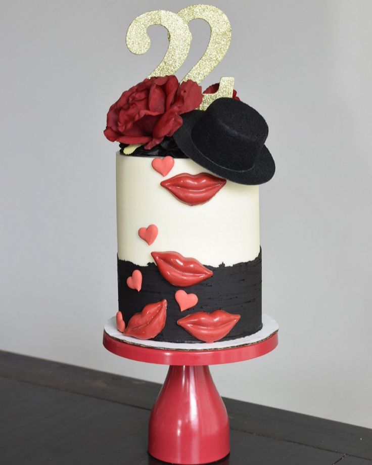 a two tiered cake decorated with lipstick and a hat