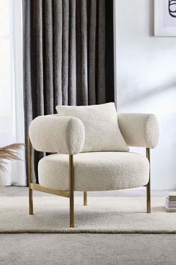 a white chair sitting on top of a rug in front of a window with curtains