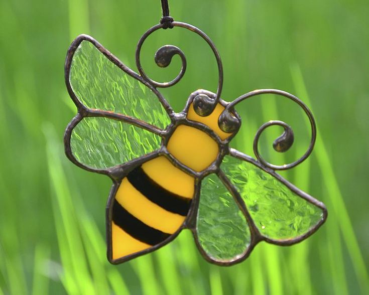 a glass bee ornament hanging from a wire on top of some green grass