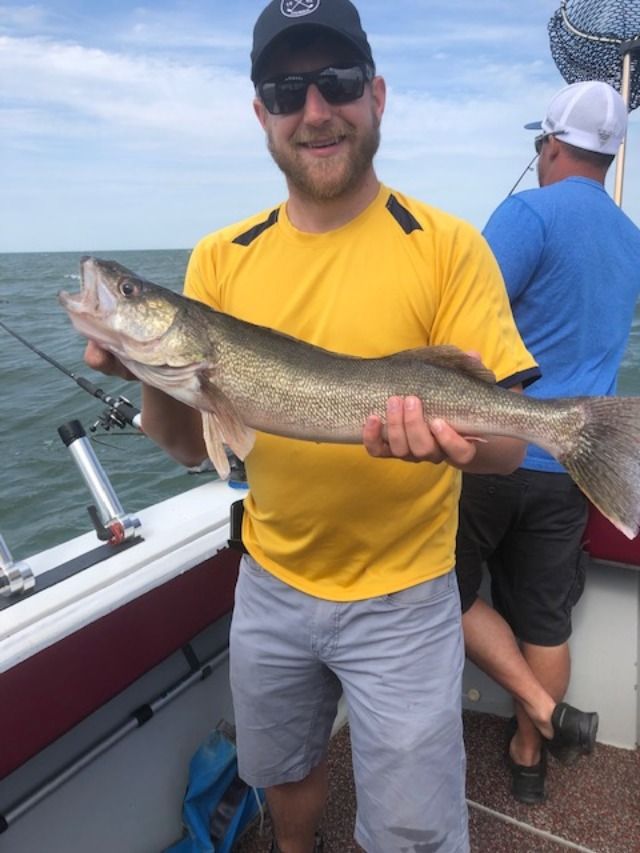 a man holding a large fish while standing on a boat