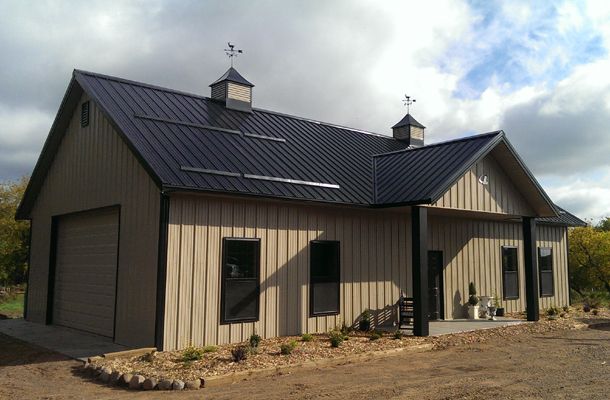 a house with a metal roof and two dormers on the top, in front of a cloudy sky