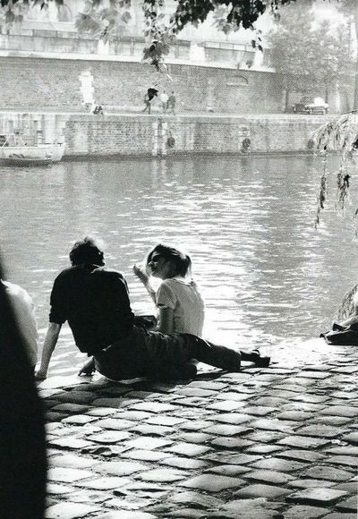 three people sitting on the ground near water