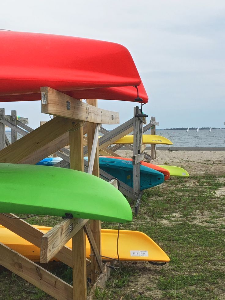 several surfboards are lined up on the grass by the water's edge in front of a wooden structure