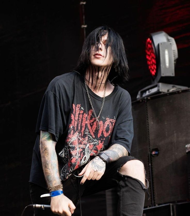 a man with black hair and piercings sitting on a stage