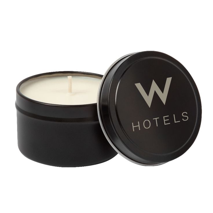 a candle in a black tin with the word hotels printed on it's lid