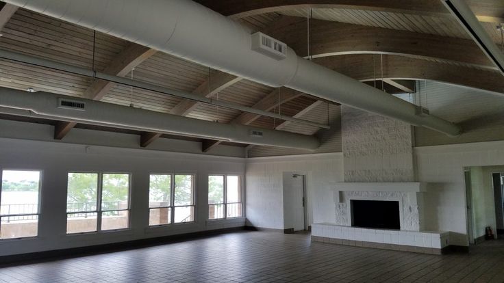 an empty room with large windows and a fireplace