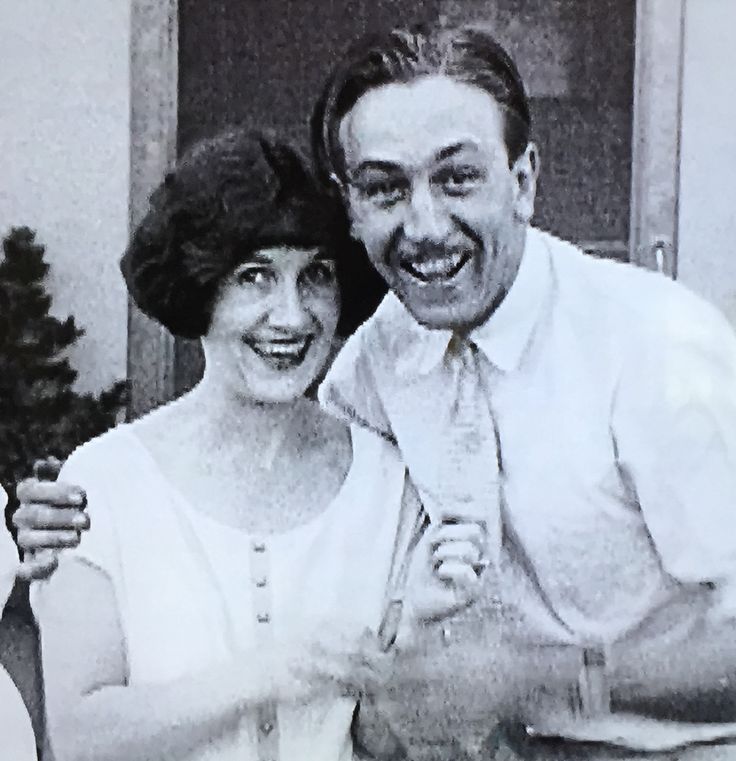 an old black and white photo of a man and woman posing for the camera with their arms around each other