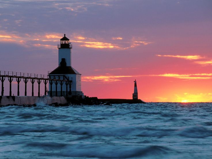 a light house sitting on top of a pier next to the ocean at sunset or dawn