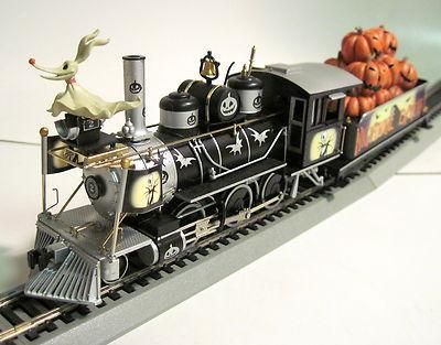 a toy train with pumpkins on the tracks and an elephant figurine next to it