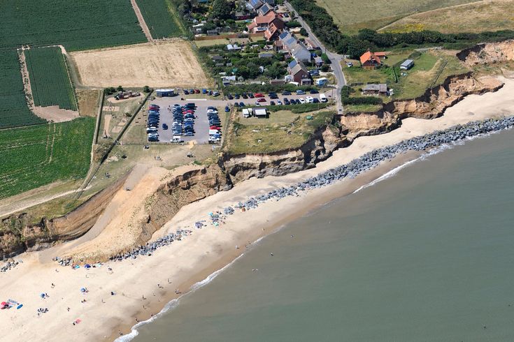 an aerial view of a beach with cars parked on the shore and houses in the background