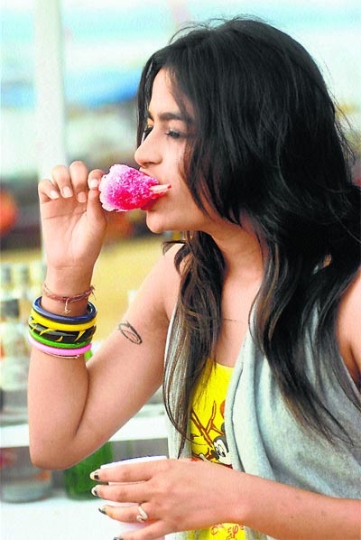 a woman with long black hair eating a pink donut