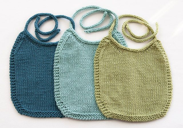 four crocheted baby bibs are shown in three different colors, one blue and one green