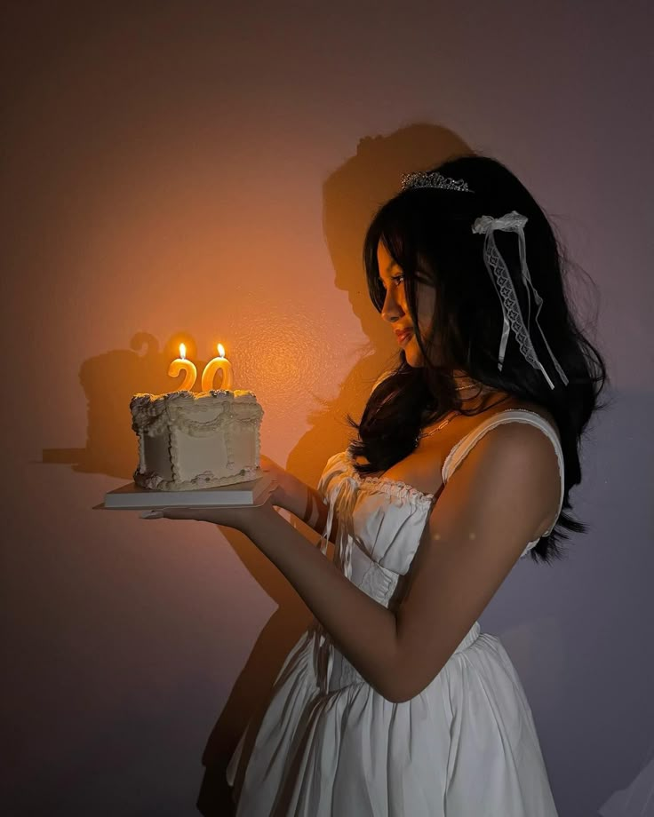 a woman holding a cake with lit candles on it