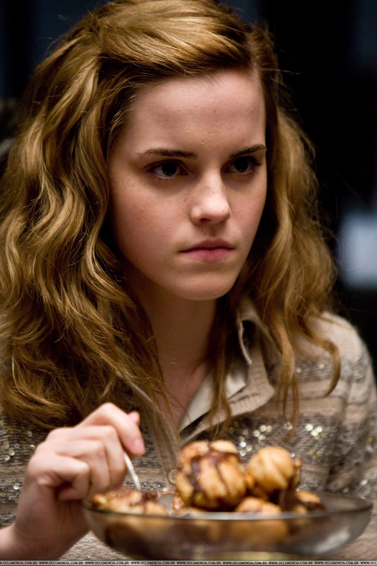 a young woman sitting at a table with a bowl of food in front of her