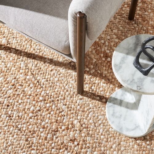 a white marble table sitting on top of a rug next to a gray chair and ottoman