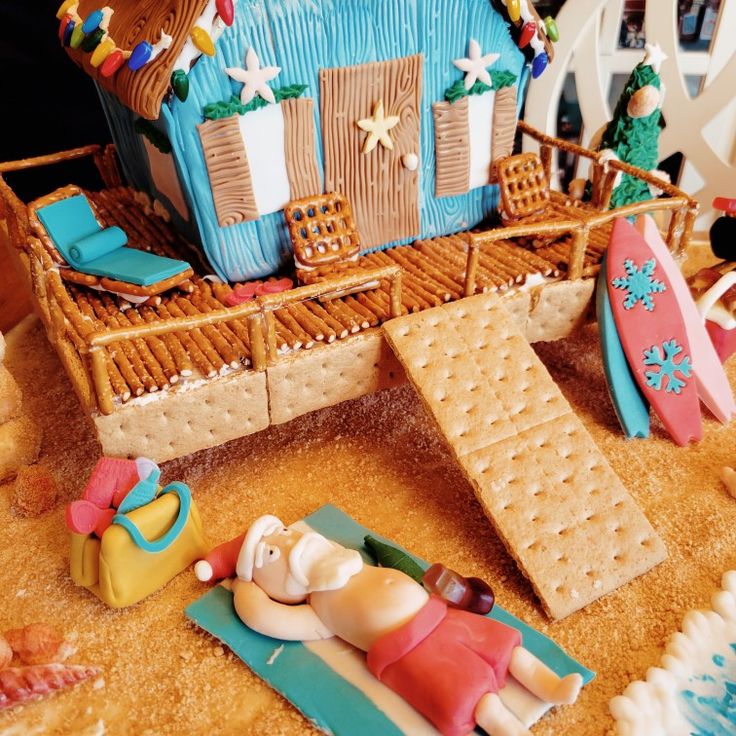 a gingerbread house decorated to look like a beach scene with people laying on the sand