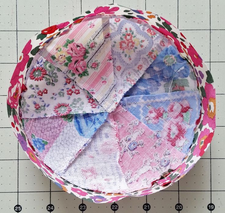 a close up of a bowl on a table with many different fabric pieces in it