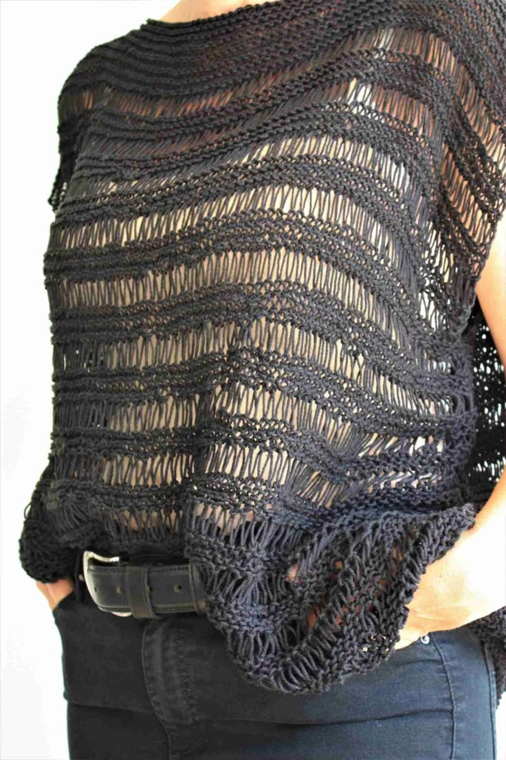 a woman is wearing a black knitted top and has her hands in her pockets