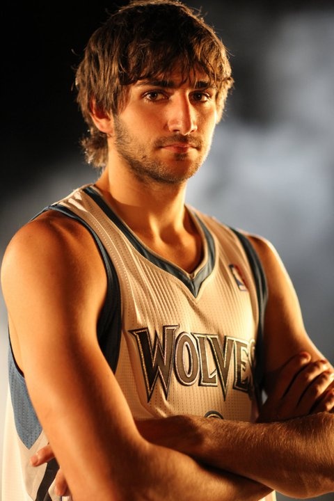 a basketball player with his arms crossed posing for a photo in front of a dark background